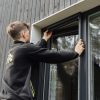 Mies asentaa Hyttysverkko ikkunaan - rullaverkkoa pystypuuvuoratun rakennuksen ikkunaan.