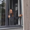 Nainen sisätiloissa irrottaa Hyttysverkko ikkunaan - kehysmallia avoimesta ikkunasta.