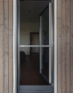 A closed glass door with a metal frame set between wooden panels